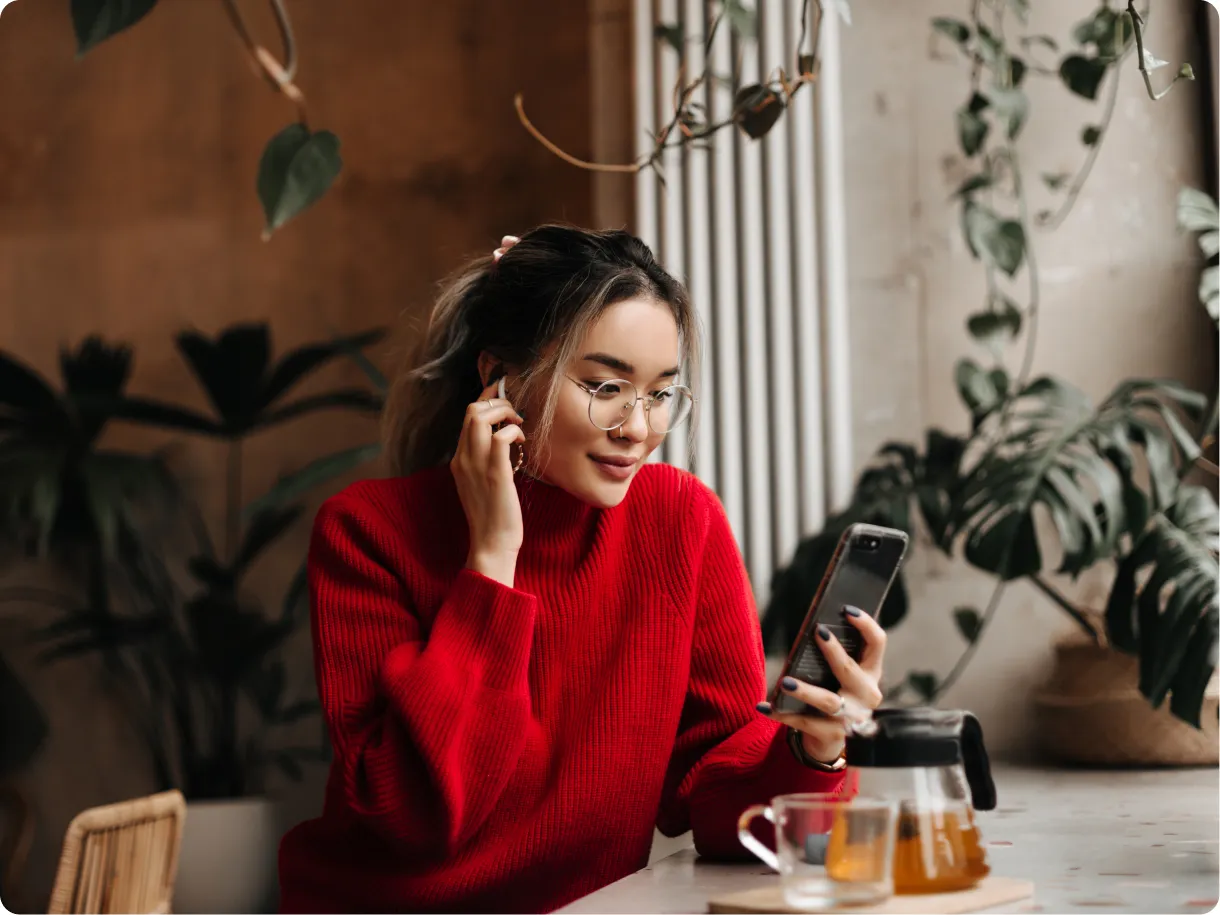 A woman in a red sweater checking her phone in a cafe