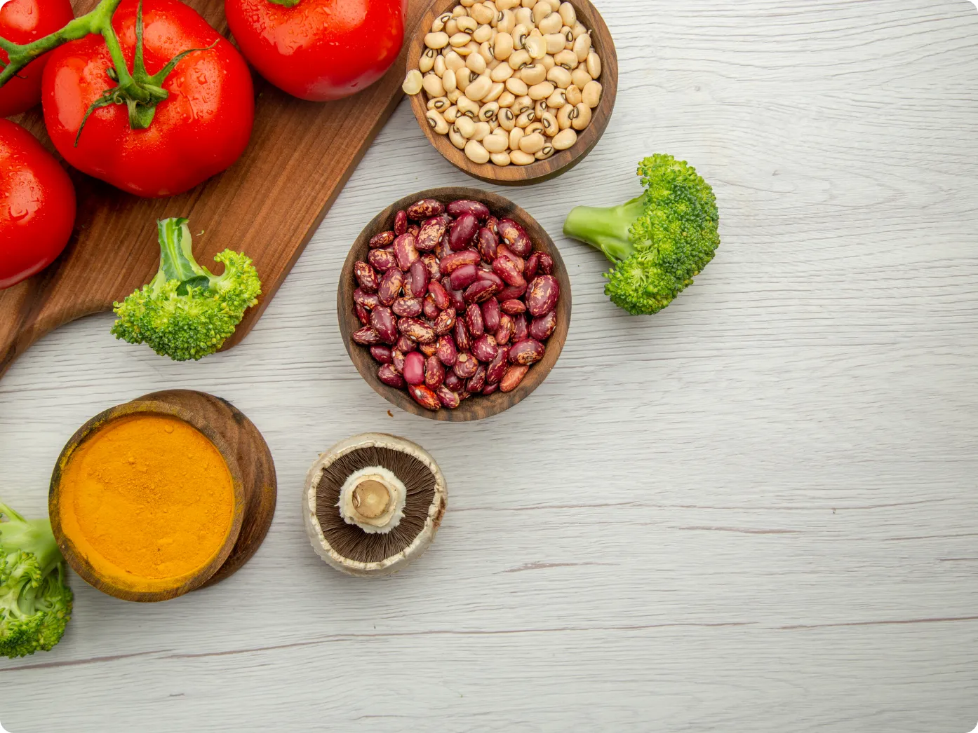 A wooden board with fresh vegetables and bowls of beans